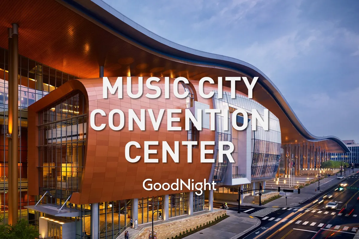 A modern exterior shot of a distinctive building with large glass windows and a colorful facade, bustling with people and surrounded by the energy of Nashville's downtown. The atmosphere is vibrant and welcoming, hinting at the property's proximity to key business and event venues like Music City Center.