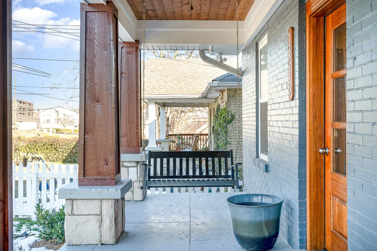 A welcoming front porch features a swing bench and planters, suggesting a relaxing, private outdoor space at Blue Pearl. The inviting setting is perfect for winding down after a day of adventure, reinforcing the idea of homey comfort and family togetherness.