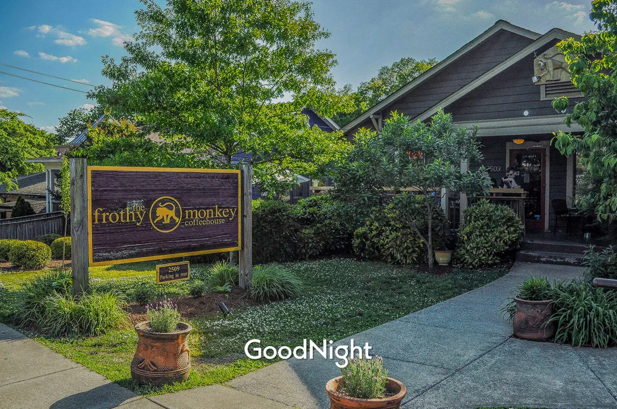 The recognizable signage and landscaped garden entrance of the Frothy Monkey coffeehouse, a local favorite. The setting feels relaxed, friendly, and quintessentially Nashville, inviting visitors to linger over coffee.