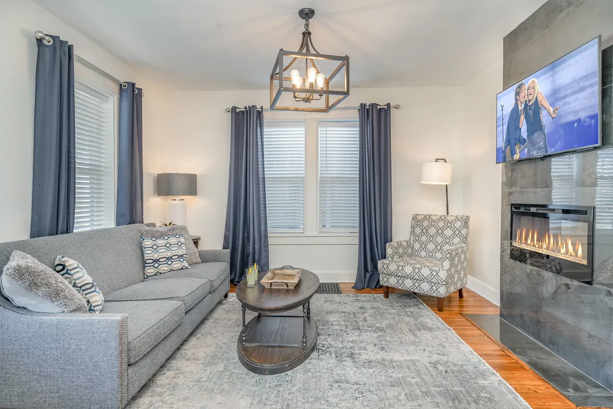 This image showcases a cozy living room complete with a plush sofa, coffee table, fireplace, TV, and armchair. The scene radiates warmth and is set up for both relaxation and entertaining guests, perfectly capturing the heart of the home.